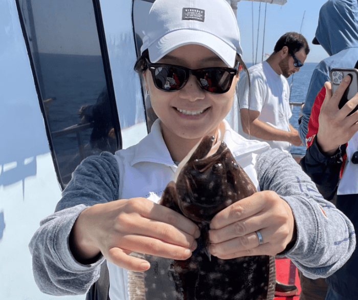 Dr. Dana Kim holding a fish on a boat